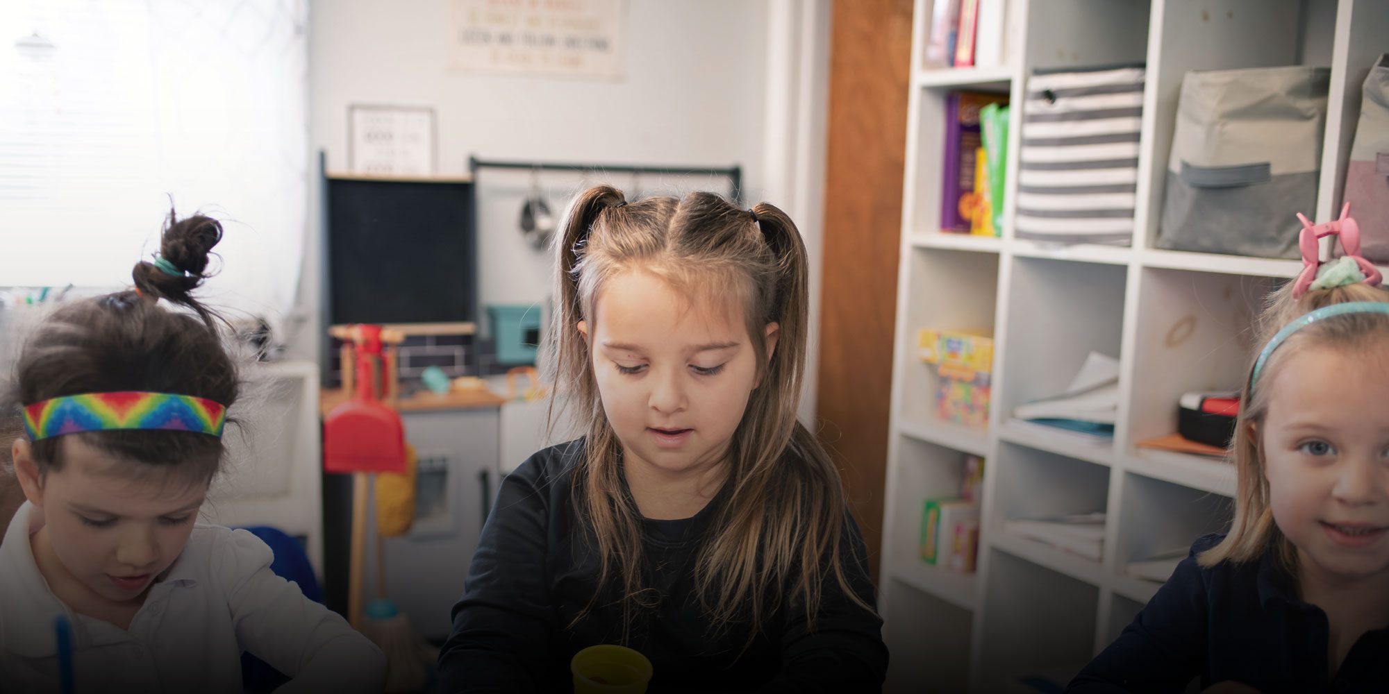 Three young students working together at a classroom table.